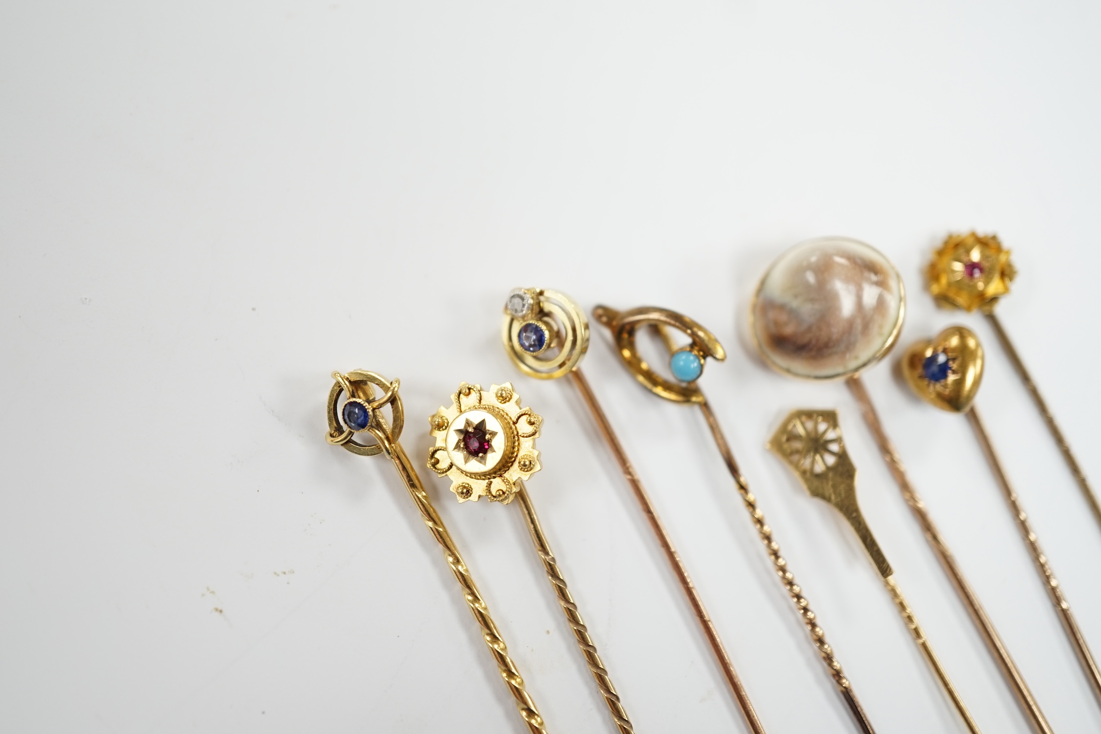 Eight assorted early 20th century and later yellow metal and gem set stick pins, including six 15ct, one 585 and one unmarked yellow metal, largest set with sapphire, 59mm, gross weight 11 grams.